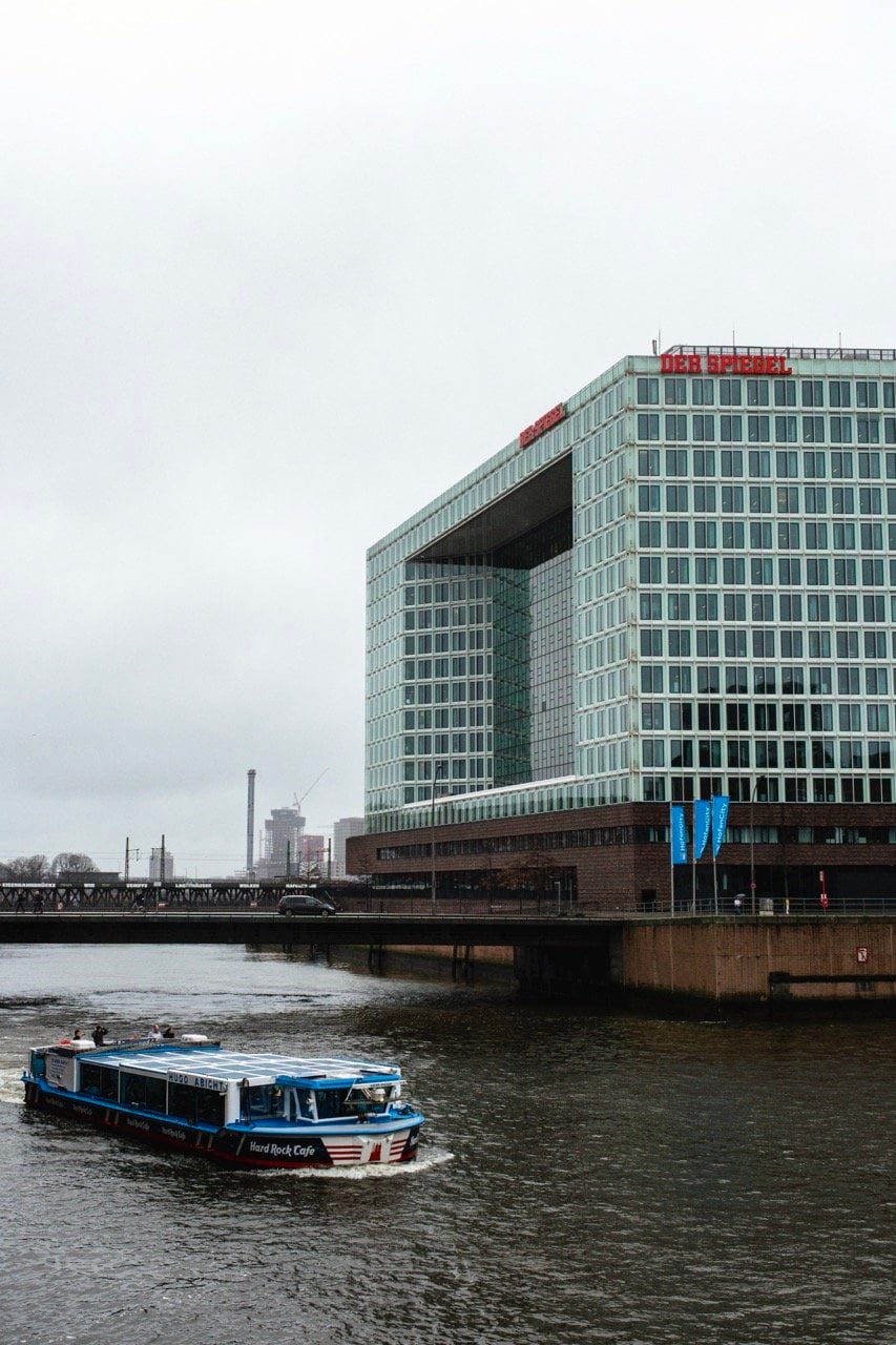 A photo of a modern building in Hamburg with a boat going past