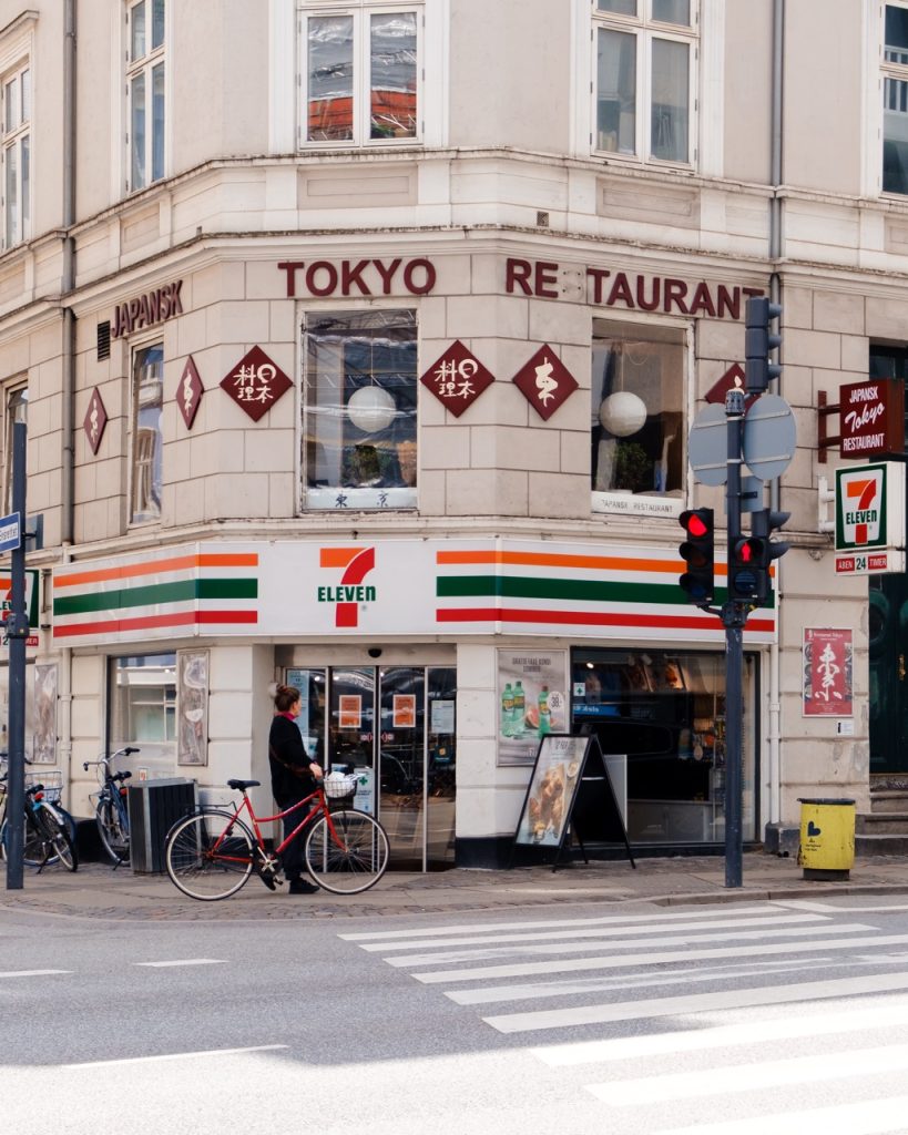 A cyclist in Vesterbro, Copenhagen, next to a 7-Eleven sign