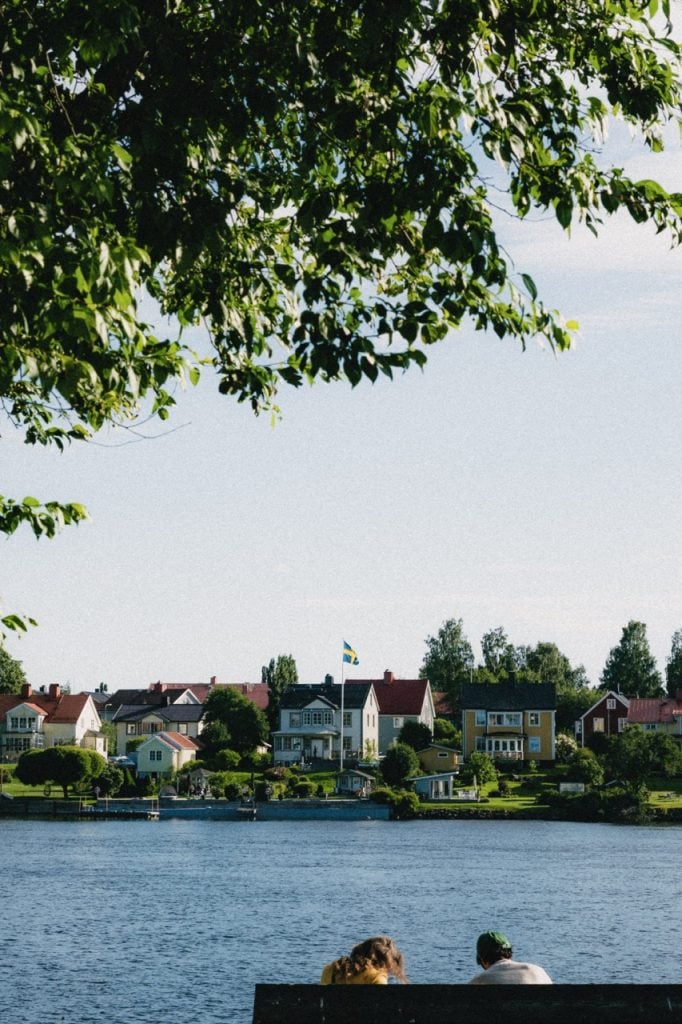 A couple sitting on a bench next to the river in Umeå