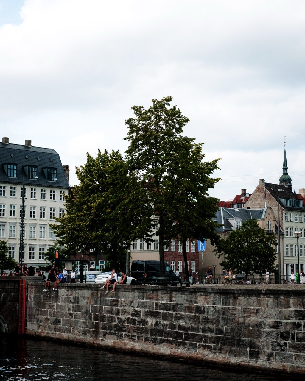 Friends sitting on the shores of Slotsholmen in Copenhagen during the summer