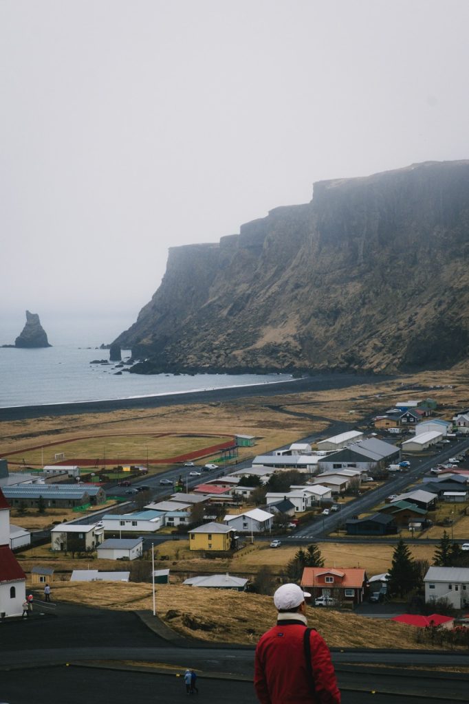 a photo of a tourist wearing a red jacket in vik, iceland