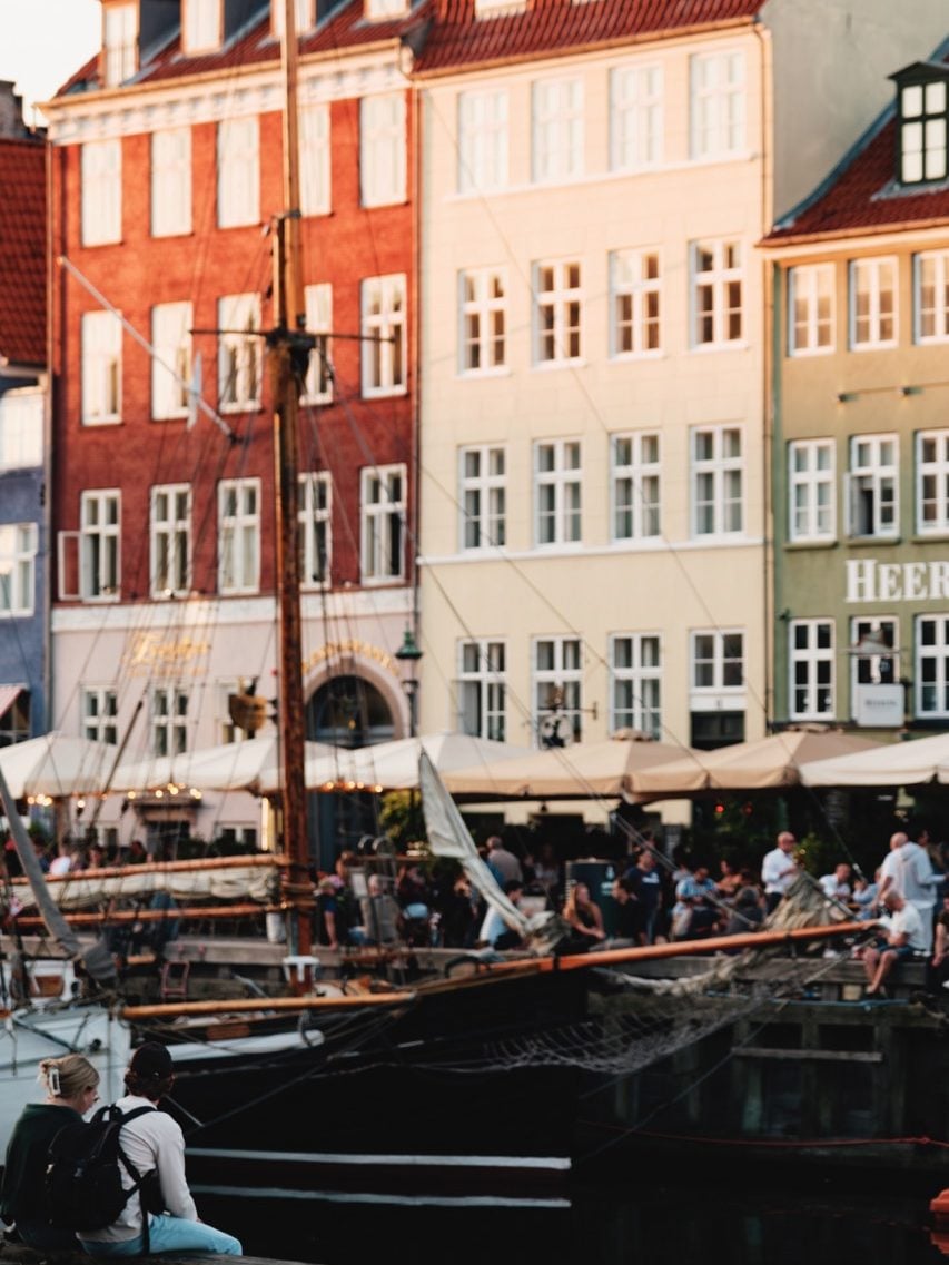 A couple sitting along the water at Nyhavn, Copenhagen