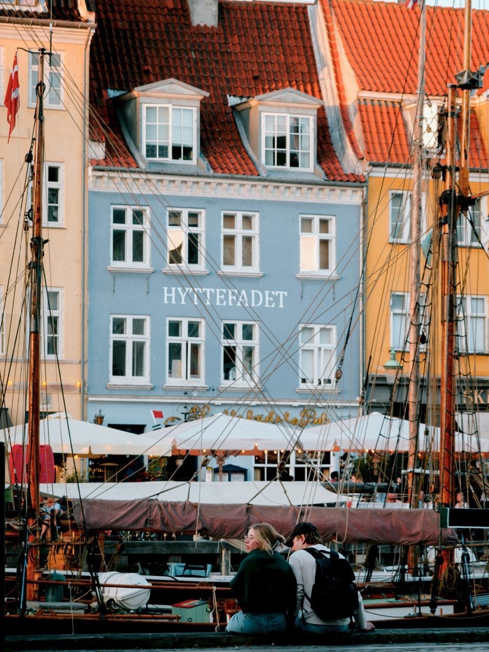 A couple sitting along the waterfont at Nyhavn