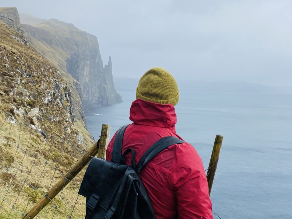 A man staring at Trøllkonufingur on the Faroe Islands