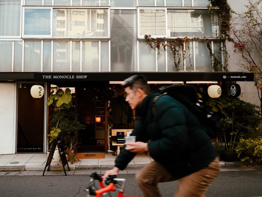 A man cycling with coffee in hand in Tokyo, Japan