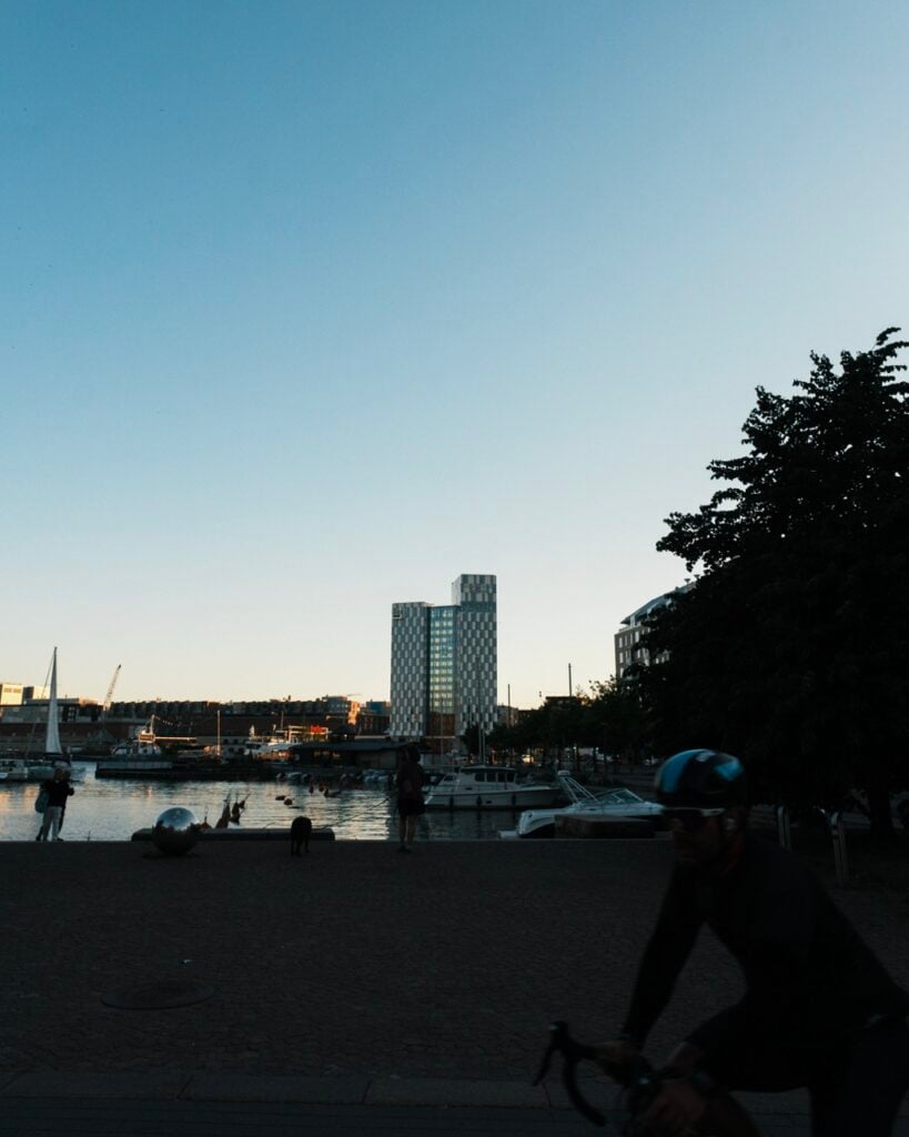 A cyclist in the summer in Helsinki, with Clarion Hotel in the background