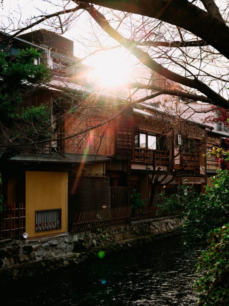 Buildings lining a river in Kyoto, Japan, with lens flare