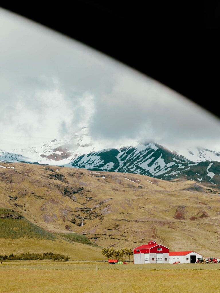 Driving past a farm and mountain in Iceland