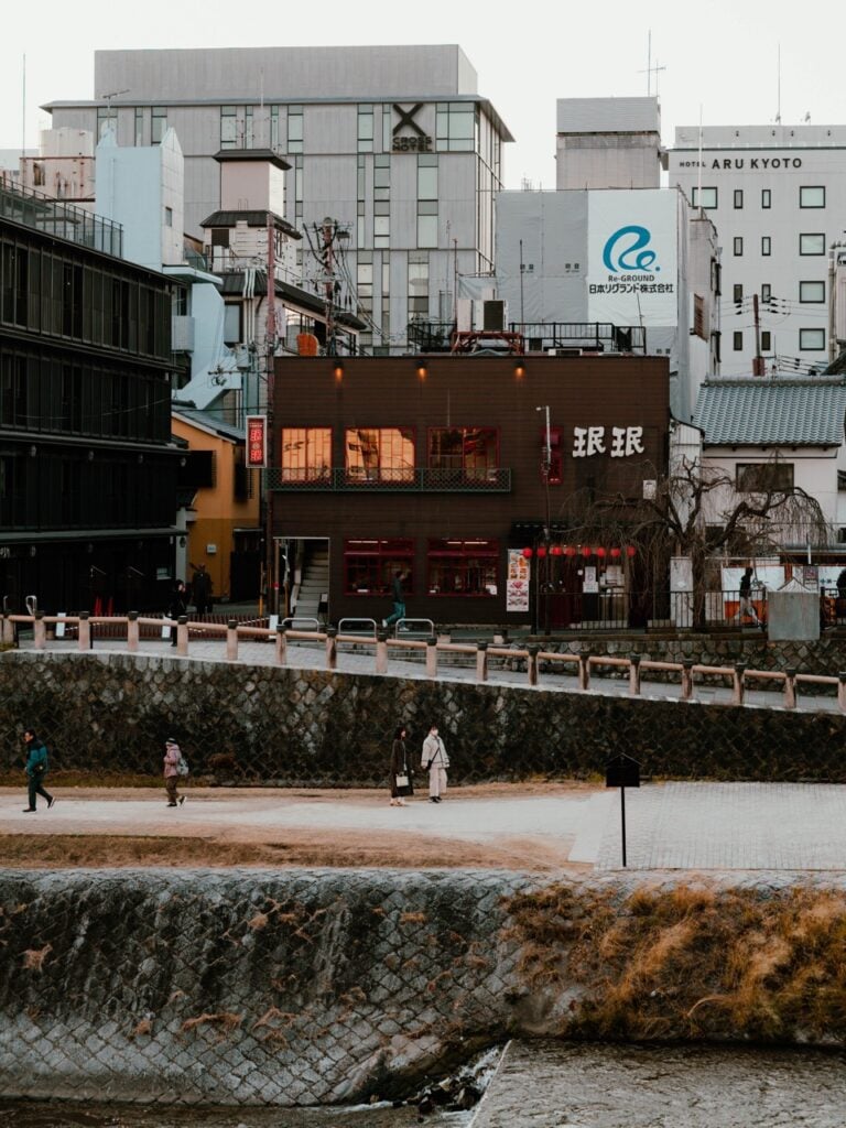 People walking along the Kamo River in Kyoto