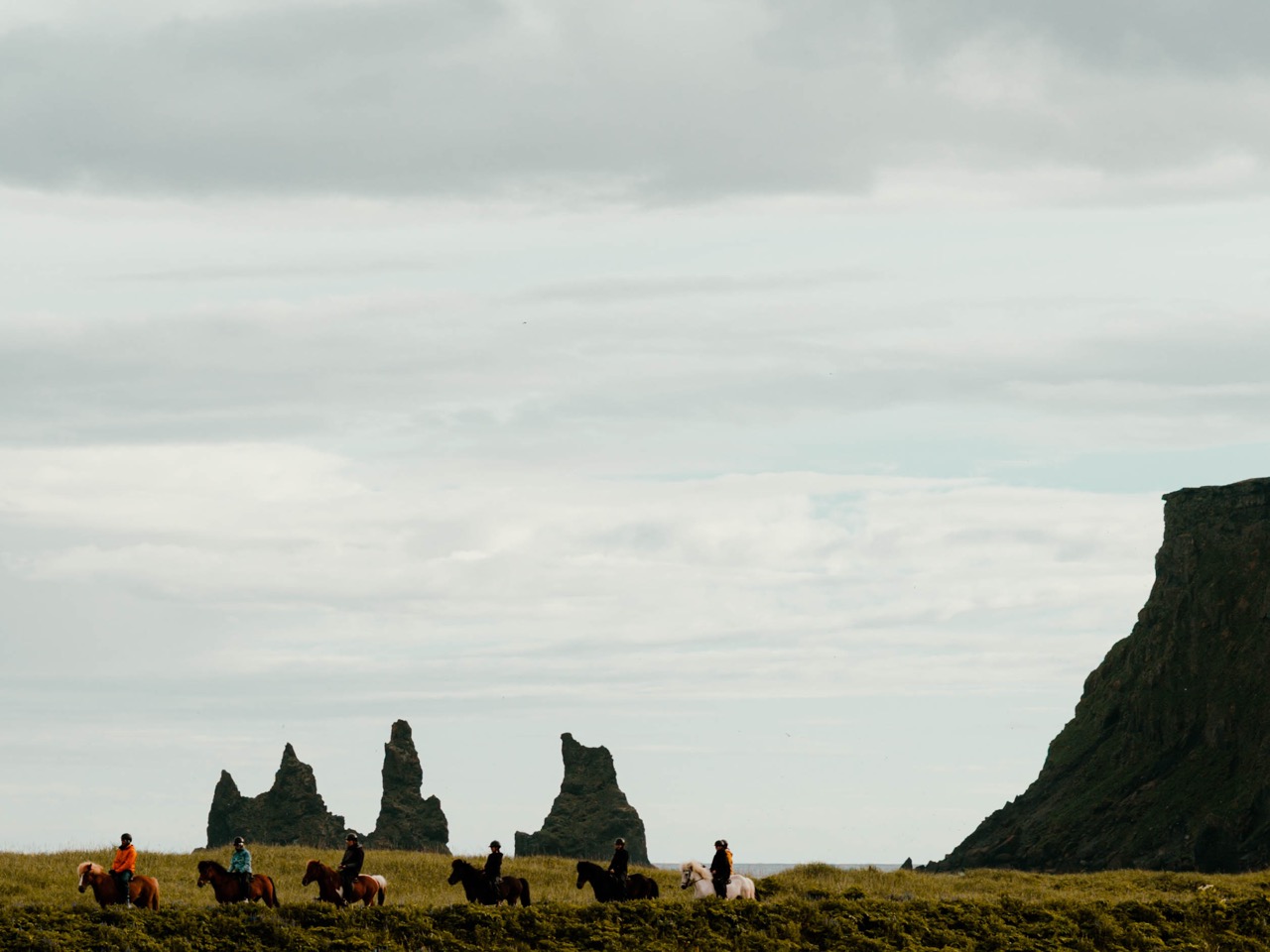 People riding horses in Vik along the beach