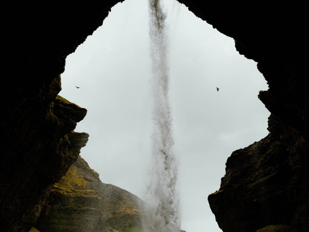 An image of Kvernufoss, Iceland, from behind the waterfall